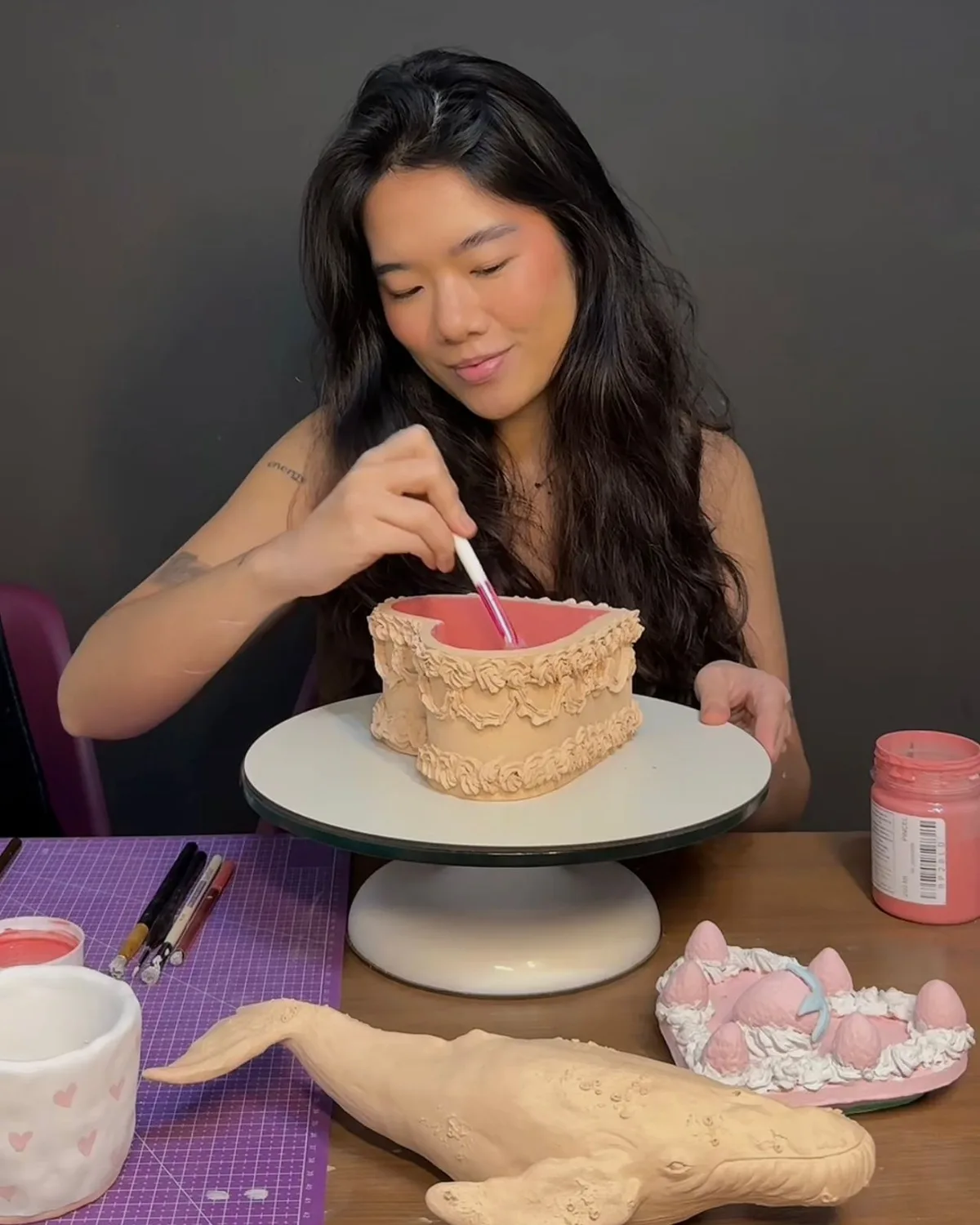 Lívia Nakahara pintando uma peça de cerâmica no ateliê